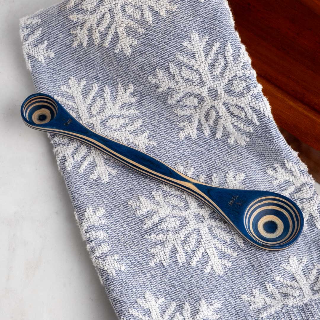 Blue wooden spoon with decorative handle on a snowflake-patterned towel